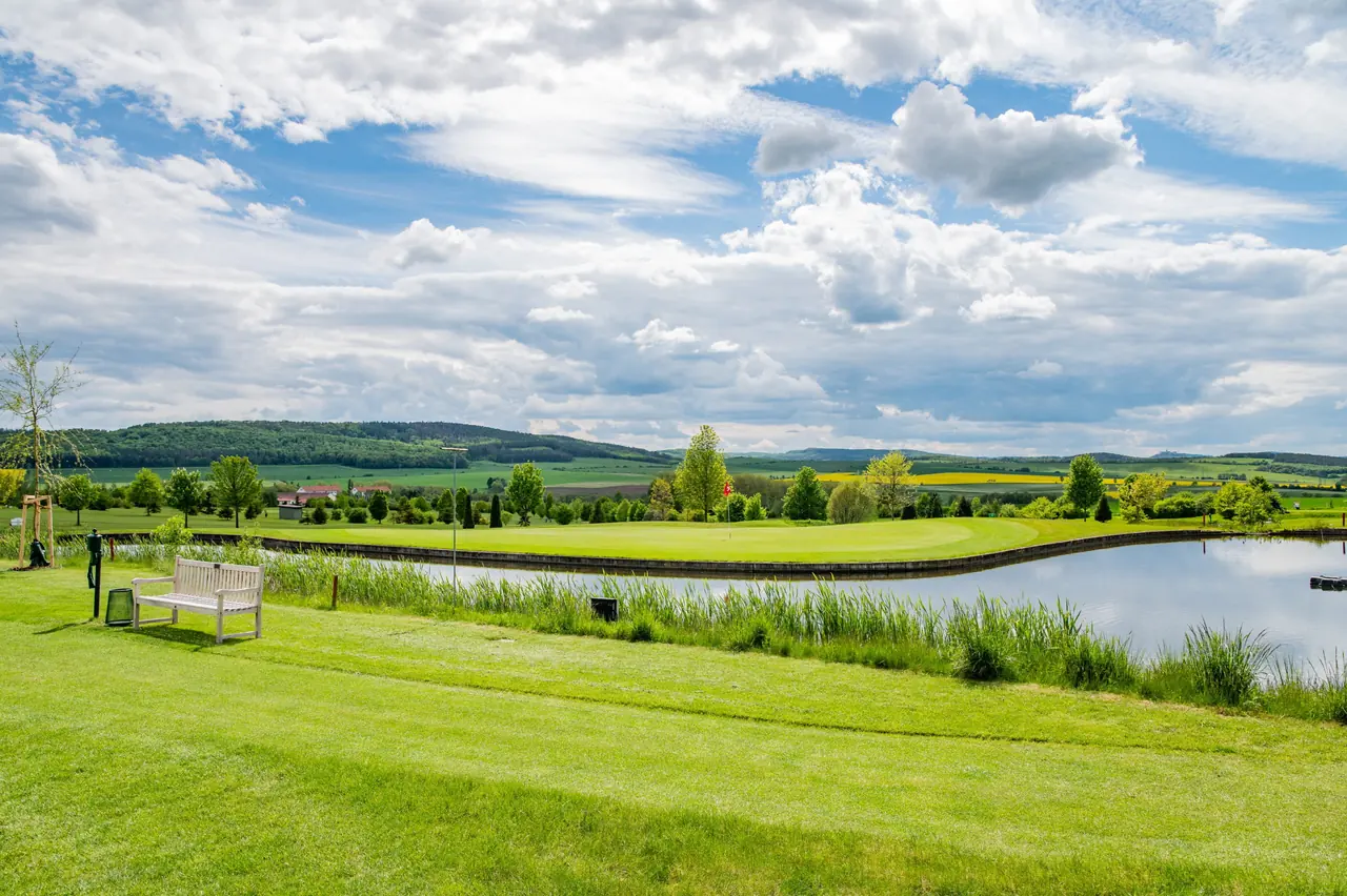 Weiter Blick über die Anlage mit Fairways, Bäumen und den Hügeln des Hainich.