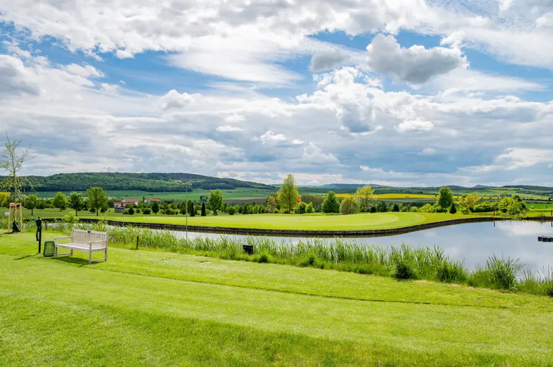 Weiter Blick über die Anlage mit Fairways, Baumreihen und den Hügeln des Hainich.